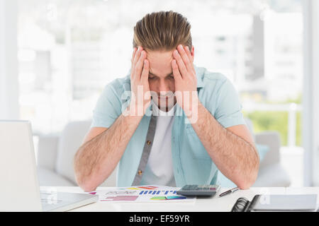 Stressed businessman covering his face at his desk Stock Photo