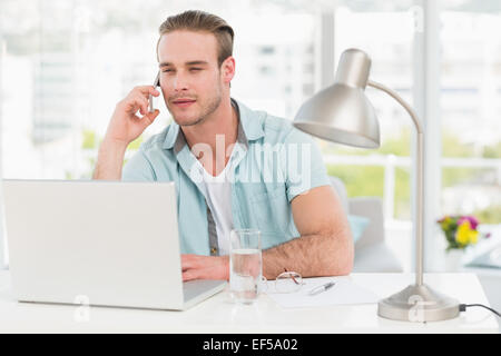 Focused businessman on the phone while using laptop Stock Photo