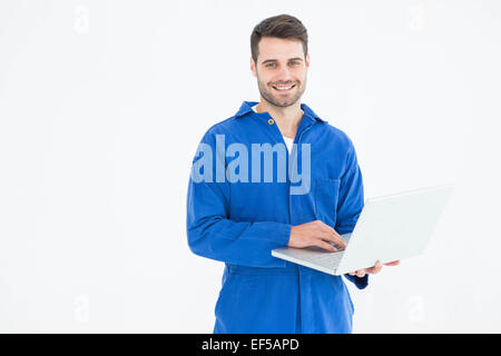 Happy young male mechanic using laptop Stock Photo