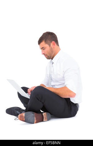 Businessman sitting on the floor using laptop Stock Photo