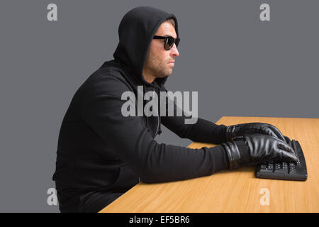 Serious burglar hacking into laptop Stock Photo