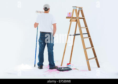 Man with paint roller standing by ladder Stock Photo