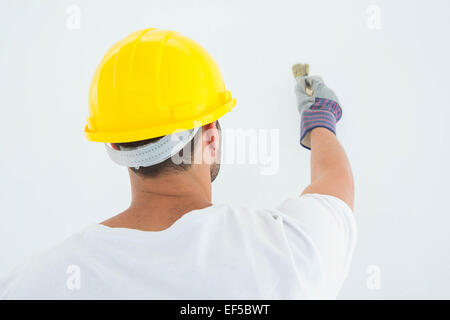 Man wearing hard hat while using paintbrush Stock Photo
