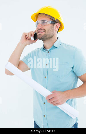 Male architect with blueprint talking on mobile phone Stock Photo