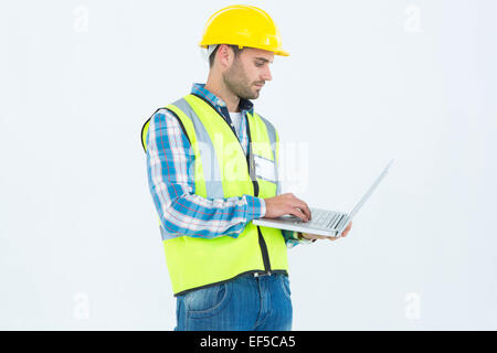 Repairman in reflective workwear using laptop Stock Photo