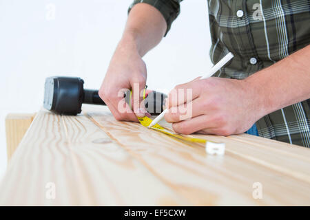 Carpenter using measure tape to mark on plank Stock Photo