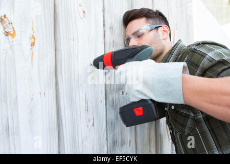 Carpenter drilling wooden cabin Stock Photo