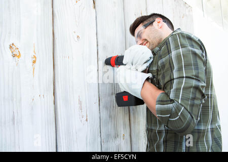 Worker using hand drill on wooden cabin Stock Photo