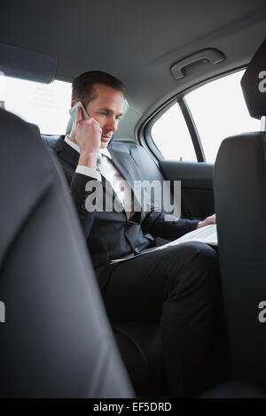 Businessman on the phone reading the newspaper Stock Photo