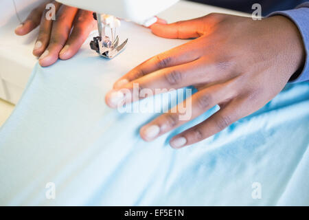 Close up of student using sewing machine Stock Photo
