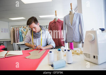 Student cutting fabric with pair of scissors Stock Photo