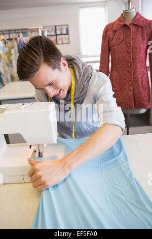 Smiling student using sewing machine Stock Photo