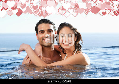 Composite image of smiling couple embracing in the pool Stock Photo