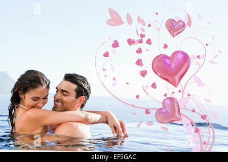 Composite image of couple hugging in the pool Stock Photo