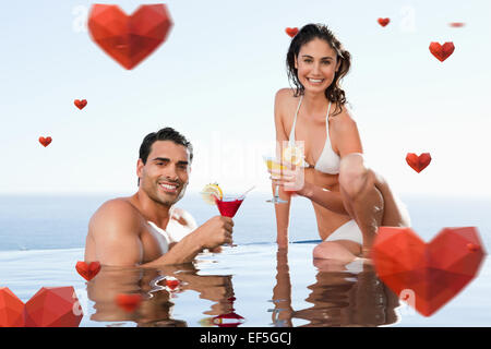 Composite image of cheerful couple having cocktails in the pool Stock Photo