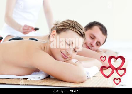 Composite image of young couple having a massage with hot stone Stock Photo