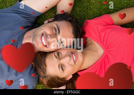 Composite image of two friends looking upwards while lying head to shoulder Stock Photo