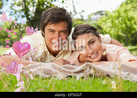 Composite image of two friends lying together on a blanket while smiling Stock Photo