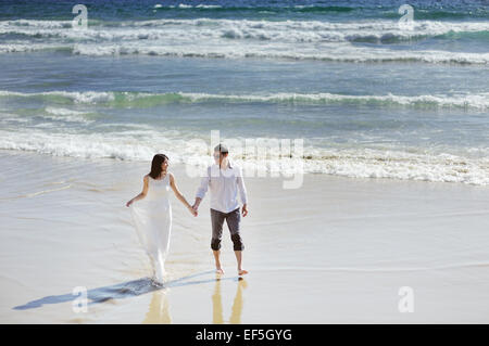 bride and groom together holding hands near sea in wedding day Stock Photo