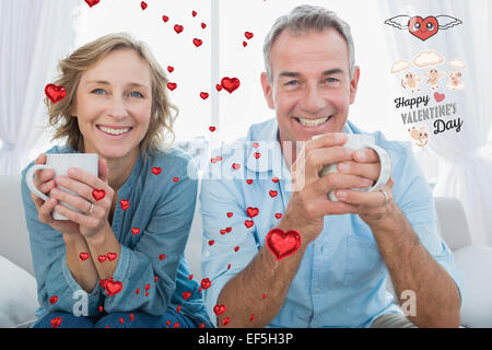 Composite image of smiling middle aged couple sitting on the couch having coffee Stock Photo