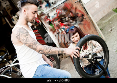 Young couple in workshop repairing bicycle Stock Photo