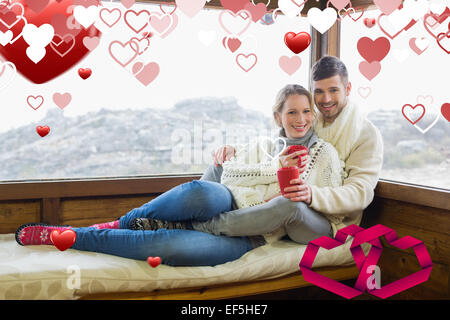 Composite image of couple in winter wear with coffee cups against cabin window Stock Photo
