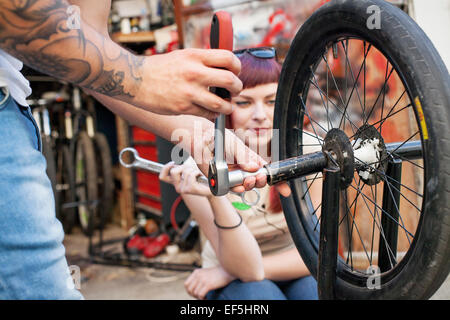 Young couple in workshop repairing BMW bicycle Stock Photo