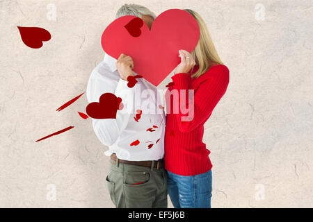 Composite image of couple embracing and holding heart over faces Stock Photo