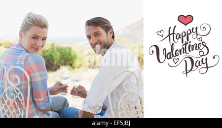 Composite image of happy young couple sitting in the garden enjoying wine together Stock Photo