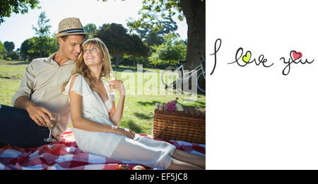 Composite image of cute couple drinking white wine on a picnic smiling at each other Stock Photo