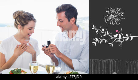 Composite image of man surprising woman with a wedding ring at lunch table Stock Photo