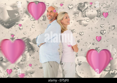 Composite image of smiling couple standing leaning backs together Stock Photo