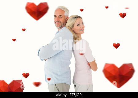 Composite image of smiling couple standing leaning backs together Stock Photo