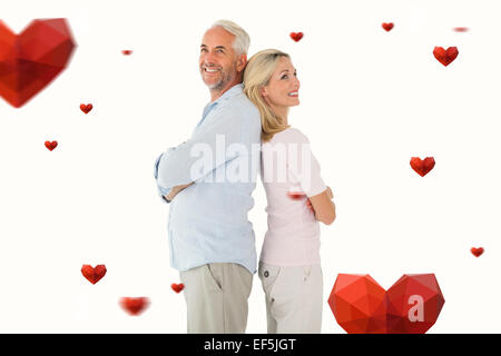 Composite image of smiling couple standing leaning backs together Stock Photo