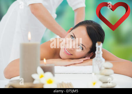 Composite image of beautiful brunette enjoying a back massage smiling at camera Stock Photo