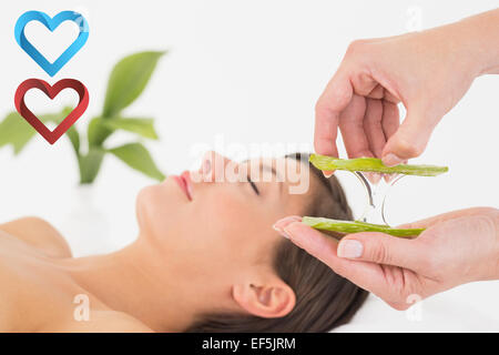 Composite image of attractive young woman receiving aloe vera massage at spa center Stock Photo
