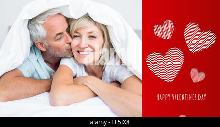 Composite image of closeup of mature man kissing womans cheek in bed Stock Photo