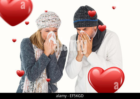 Composite image of sick couple in winter fashion sneezing Stock Photo