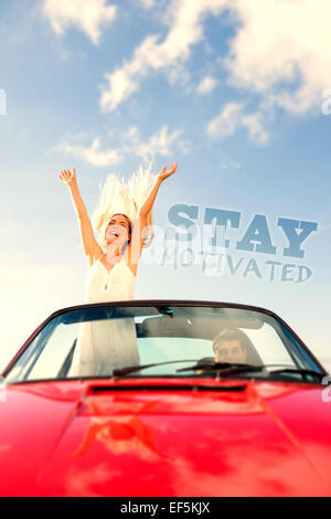 Composite image of happy woman standing in cabriolet while her boyfriend driving Stock Photo