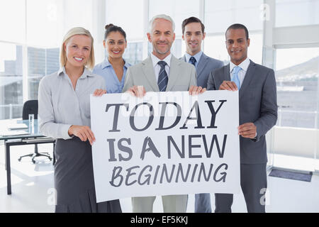 Composite image of business team holding large blank poster Stock Photo