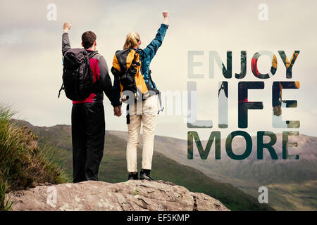 Composite image of excited couple reaching the top of their hike and cheering Stock Photo