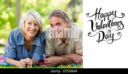 Composite image of couple lying on blanket in park Stock Photo