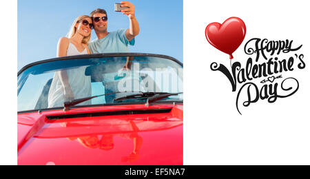 Composite image of smiling couple standing in red cabriolet taking picture Stock Photo
