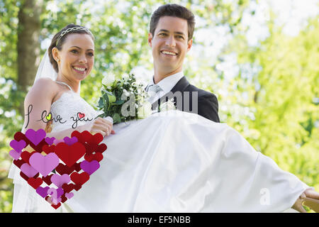 Composite image of groom carrying bride in garden Stock Photo