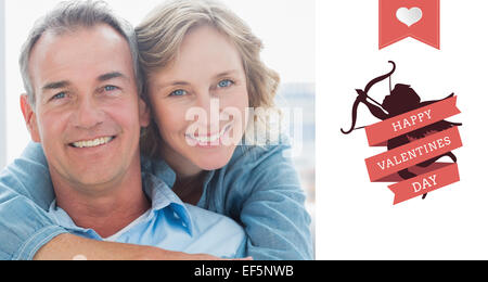 Composite image of smiling woman hugging her husband on the couch from behind Stock Photo