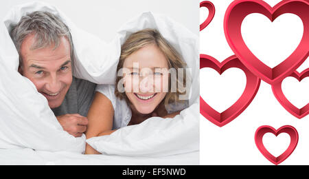 Composite image of happy middle aged couple under the duvet Stock Photo