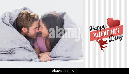 Composite image of couple wrapped in the duvet Stock Photo