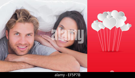 Composite image of beautiful couple smiling under the cover Stock Photo