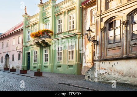 Pastel colored buildings with flower boxes and iron lampposts  on a cobblestone street in Banska Stiavnica, Slovakia Stock Photo