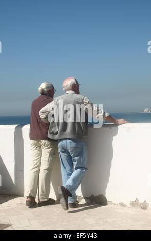 Retired couple standing by wall, looking at view in Sitges, near Barcelona, Catalonia Stock Photo